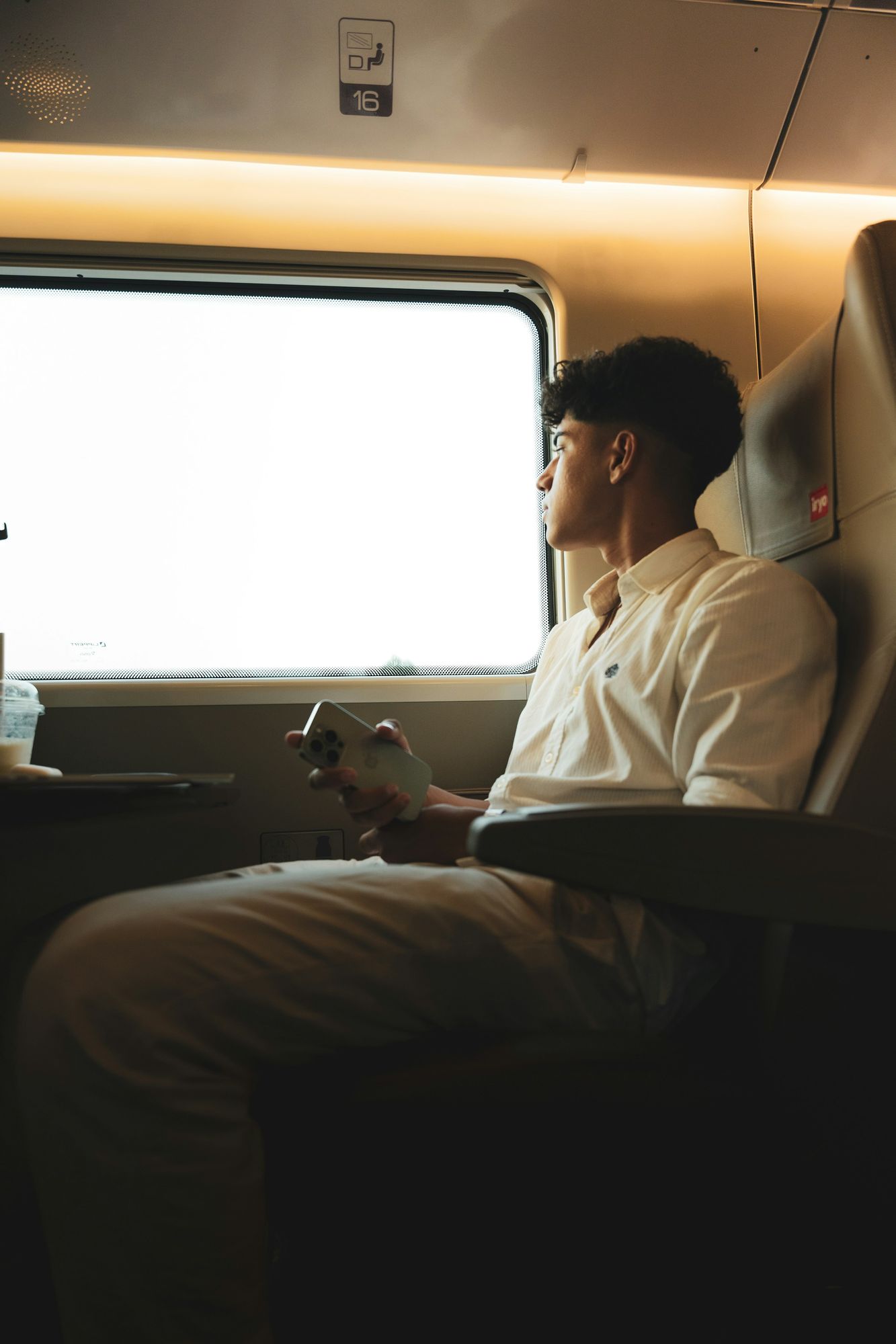 A man looking out the window of a commuter train