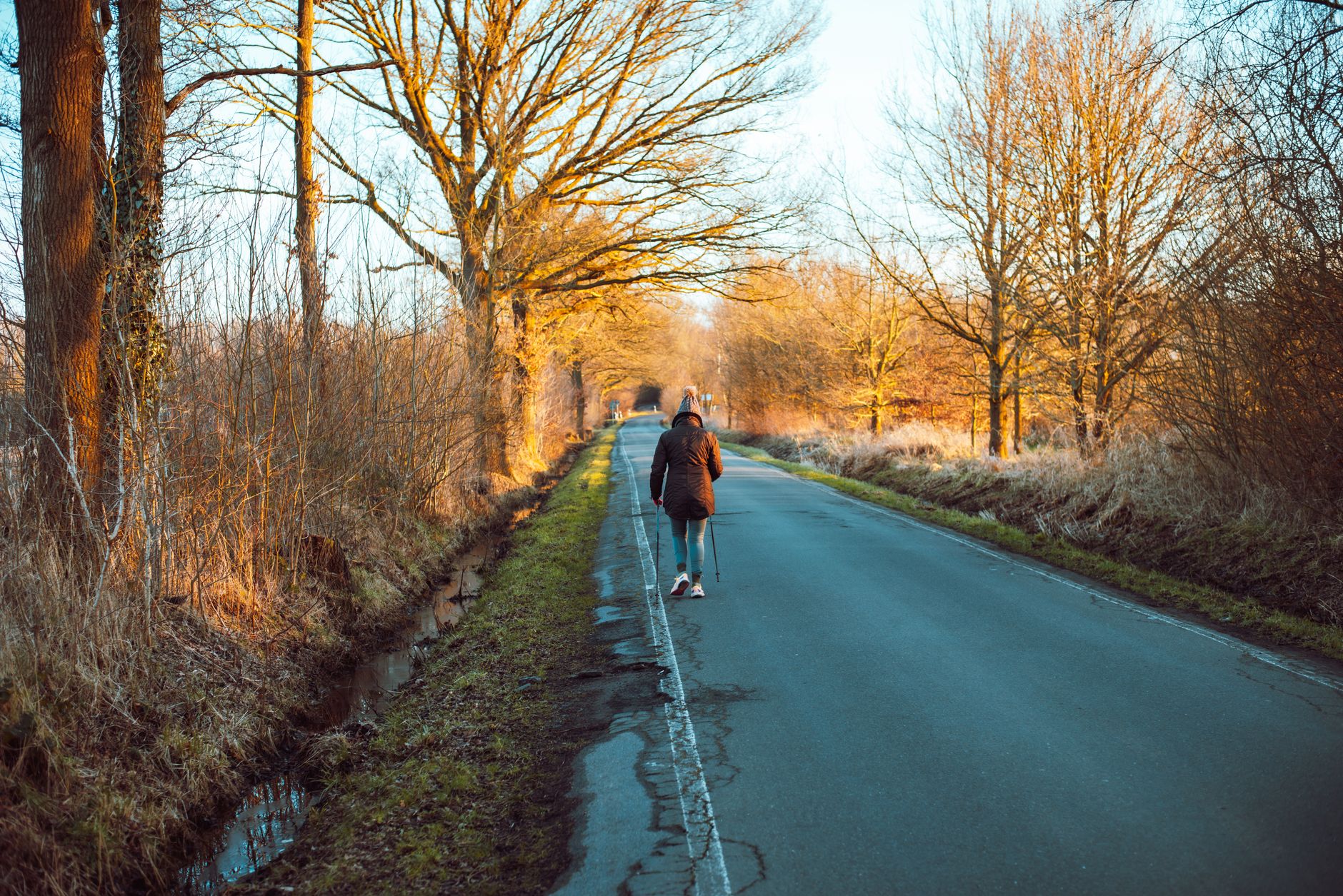 A person walking down a quiet road in morning light