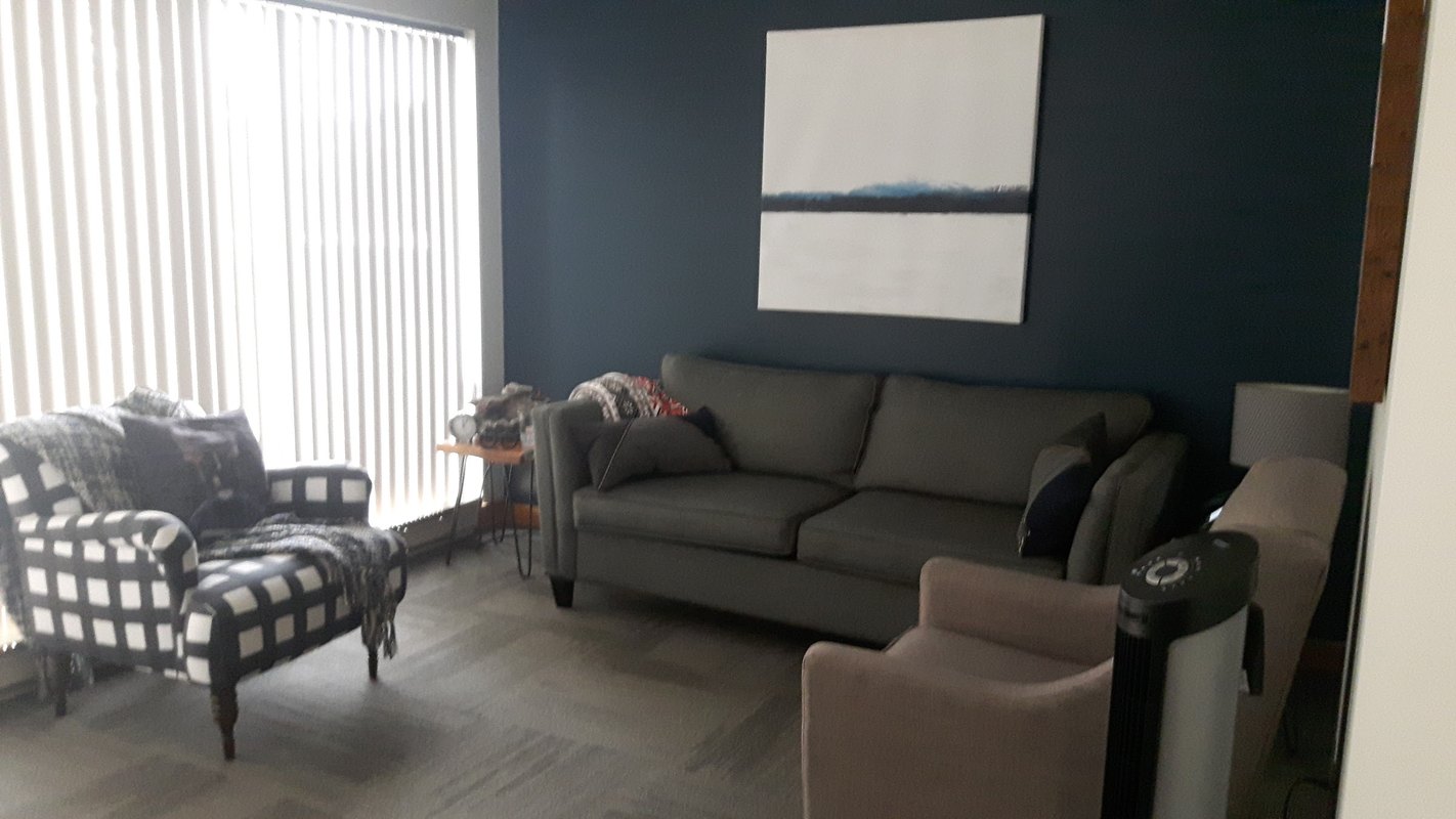 A therapy room at the Burlington office, with a sofa and armchairs under a framed print