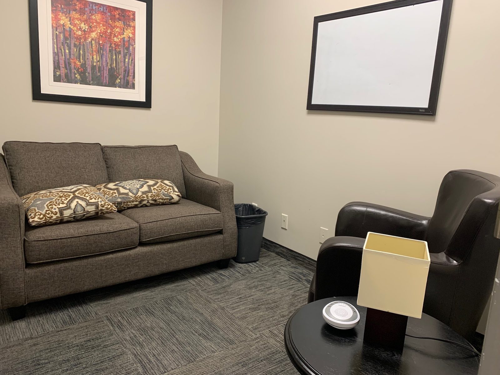 A therapy room at the Hamilton office, with a sofa, a leather armchair and a side table