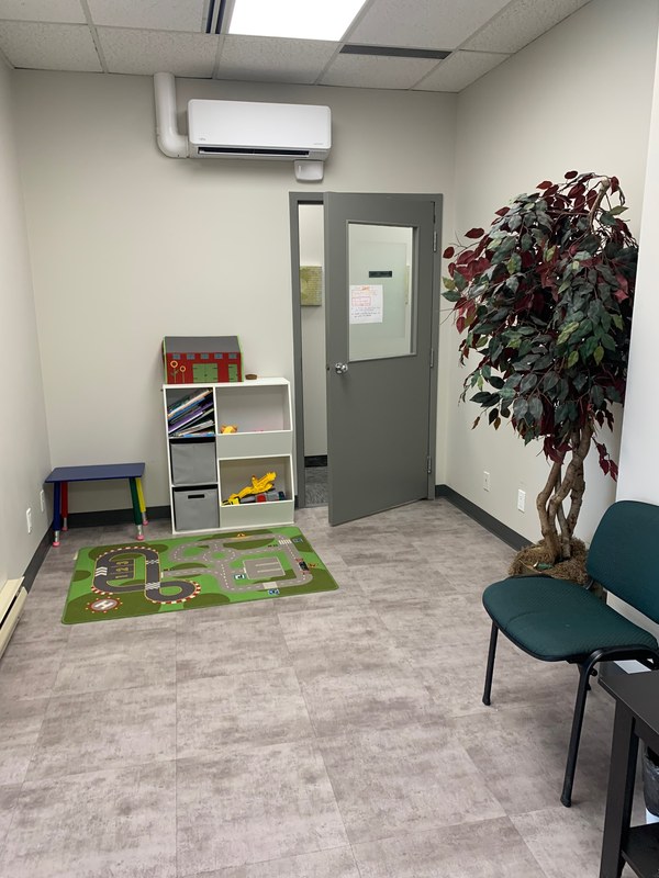 The children's room at the Hamilton office, with a play mat, toy shelves and a small chair