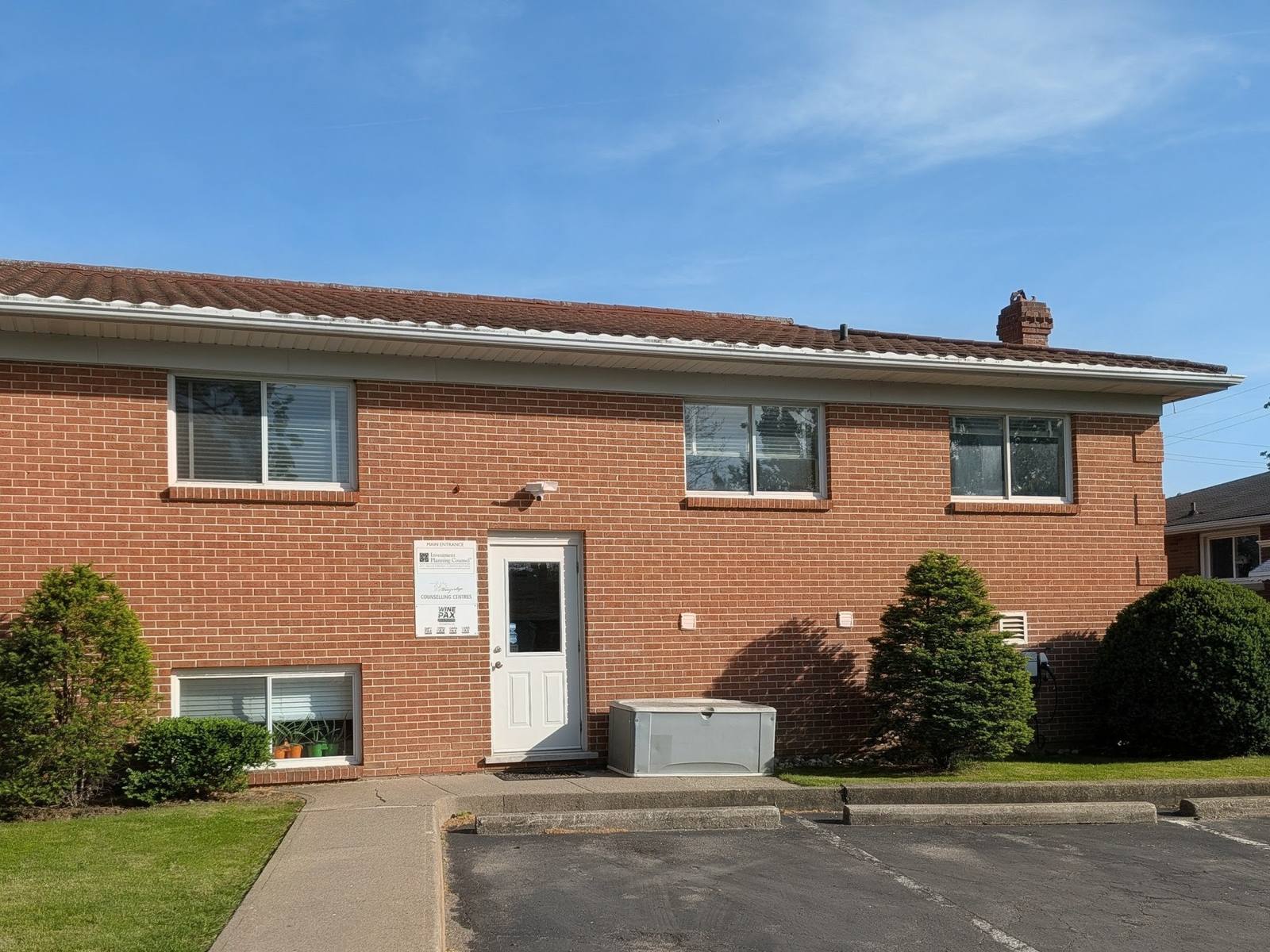 The two-storey brick building that houses the St. Catharines office, with parking in front