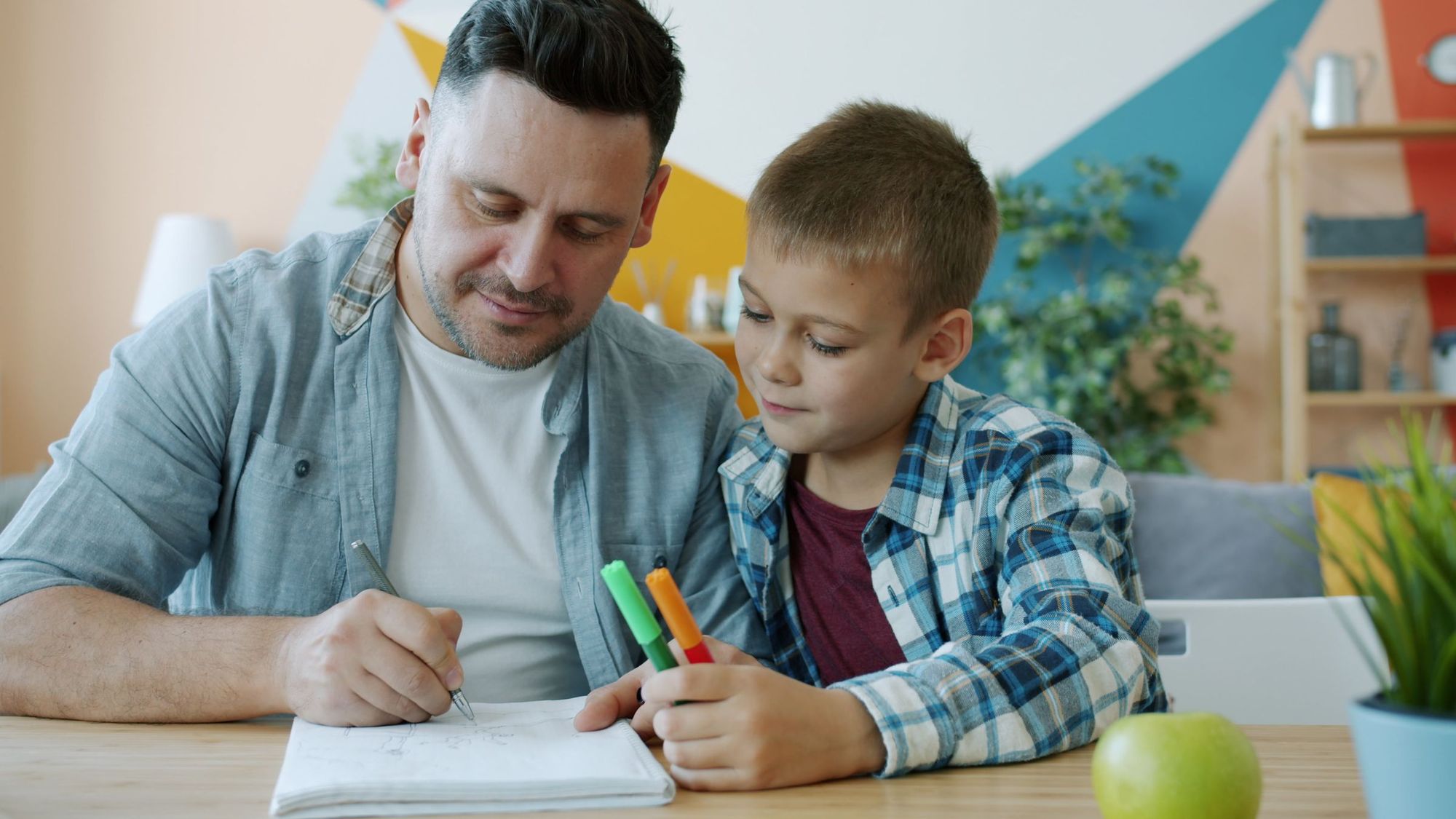 A father and son doing homework together at a table