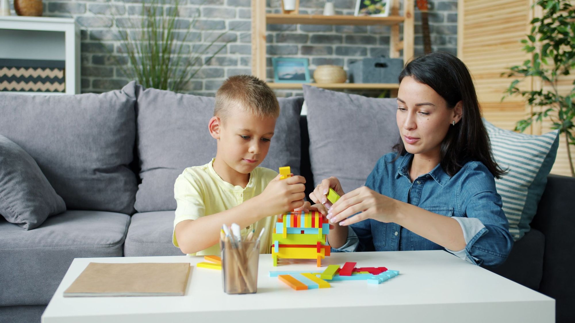 A mother and son building a colourful block set at a table