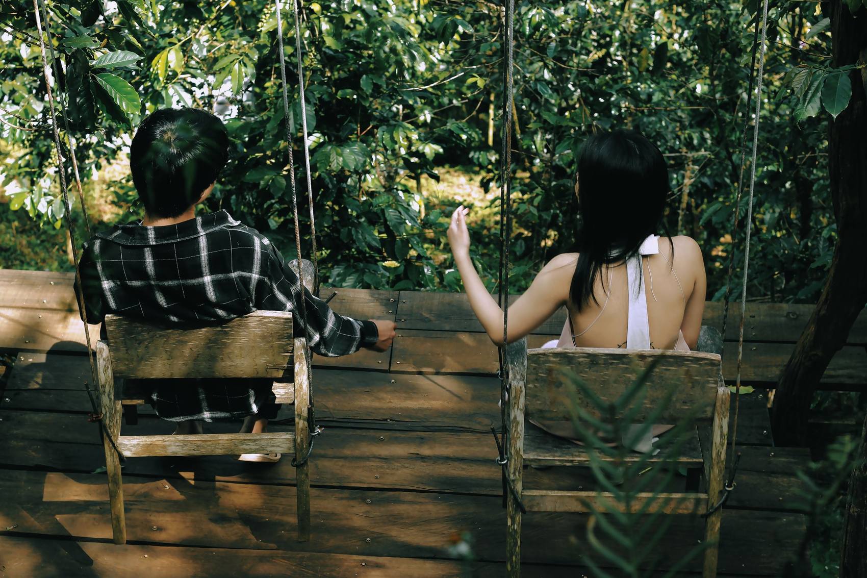 Two people sitting in garden chairs among plants