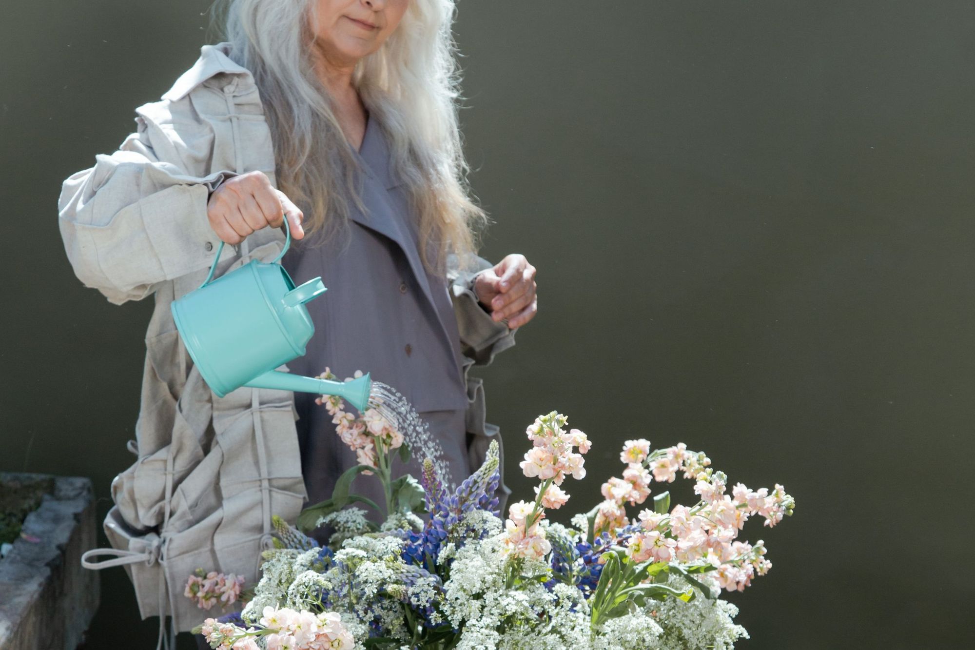 An older woman watering flowers