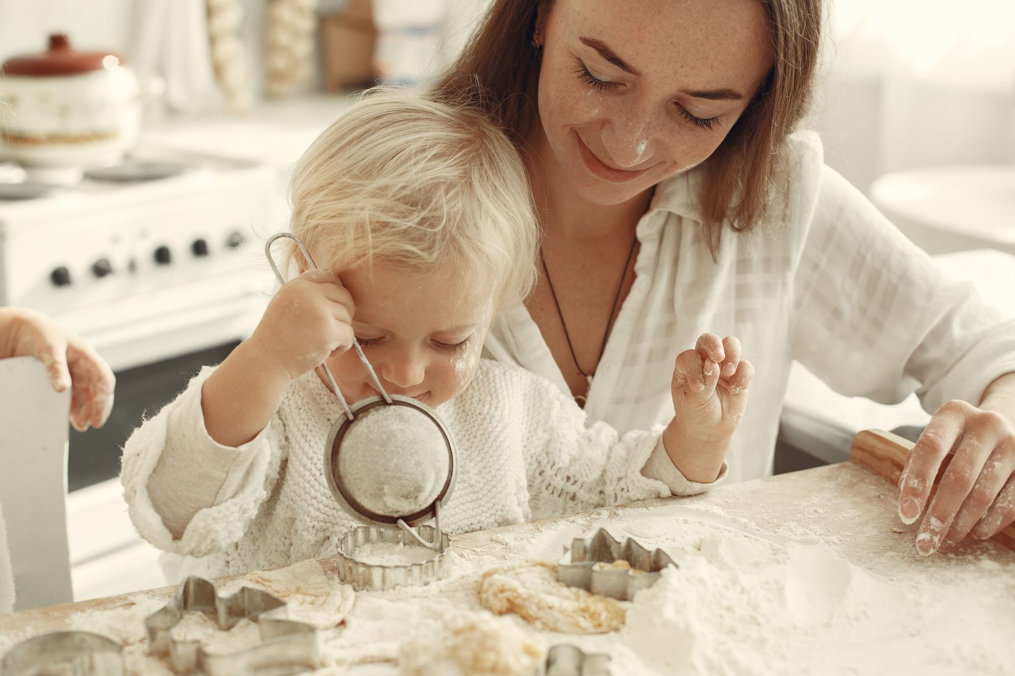 A mother and toddler playing with flour at the kitchen table