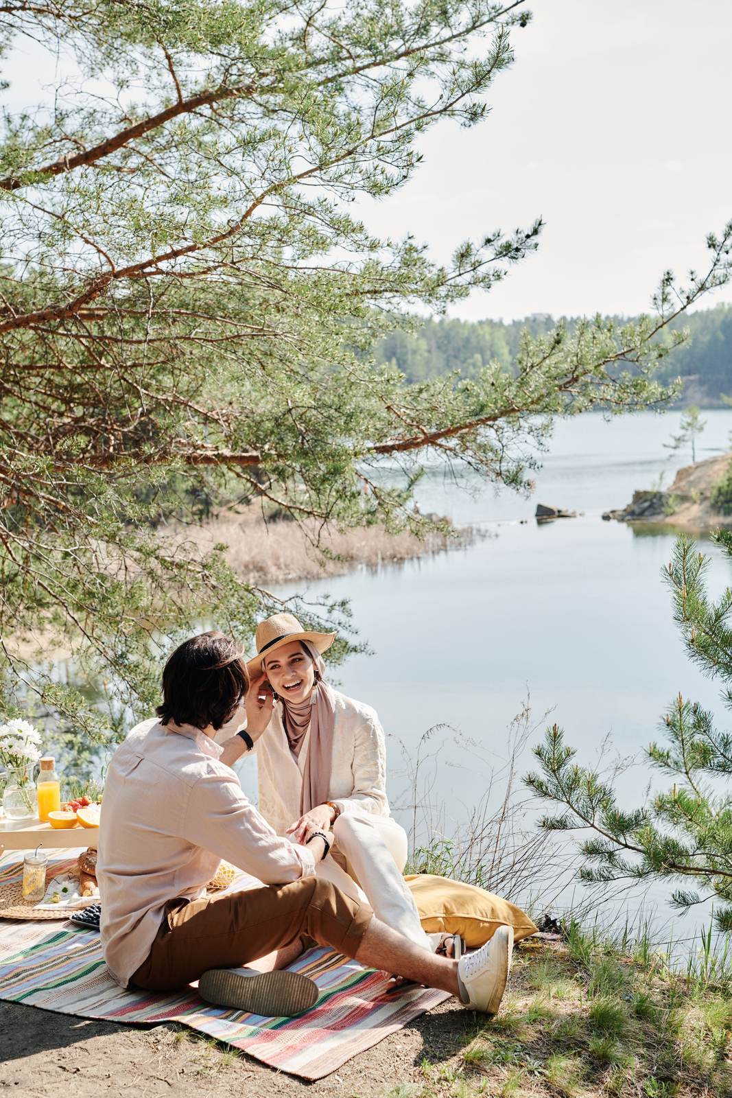 A couple sitting together on a blanket by a lake