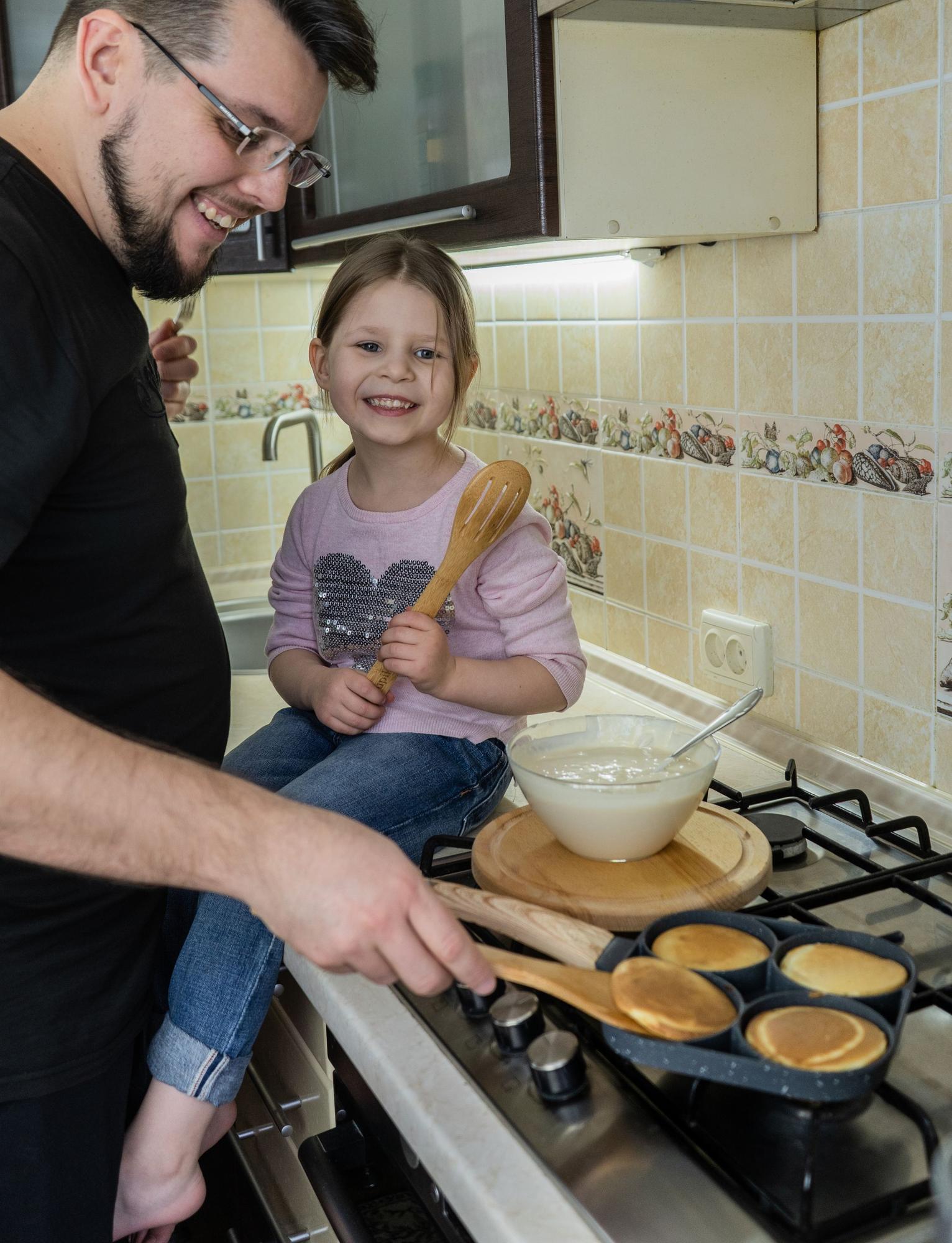 A father making pancakes with his daughter