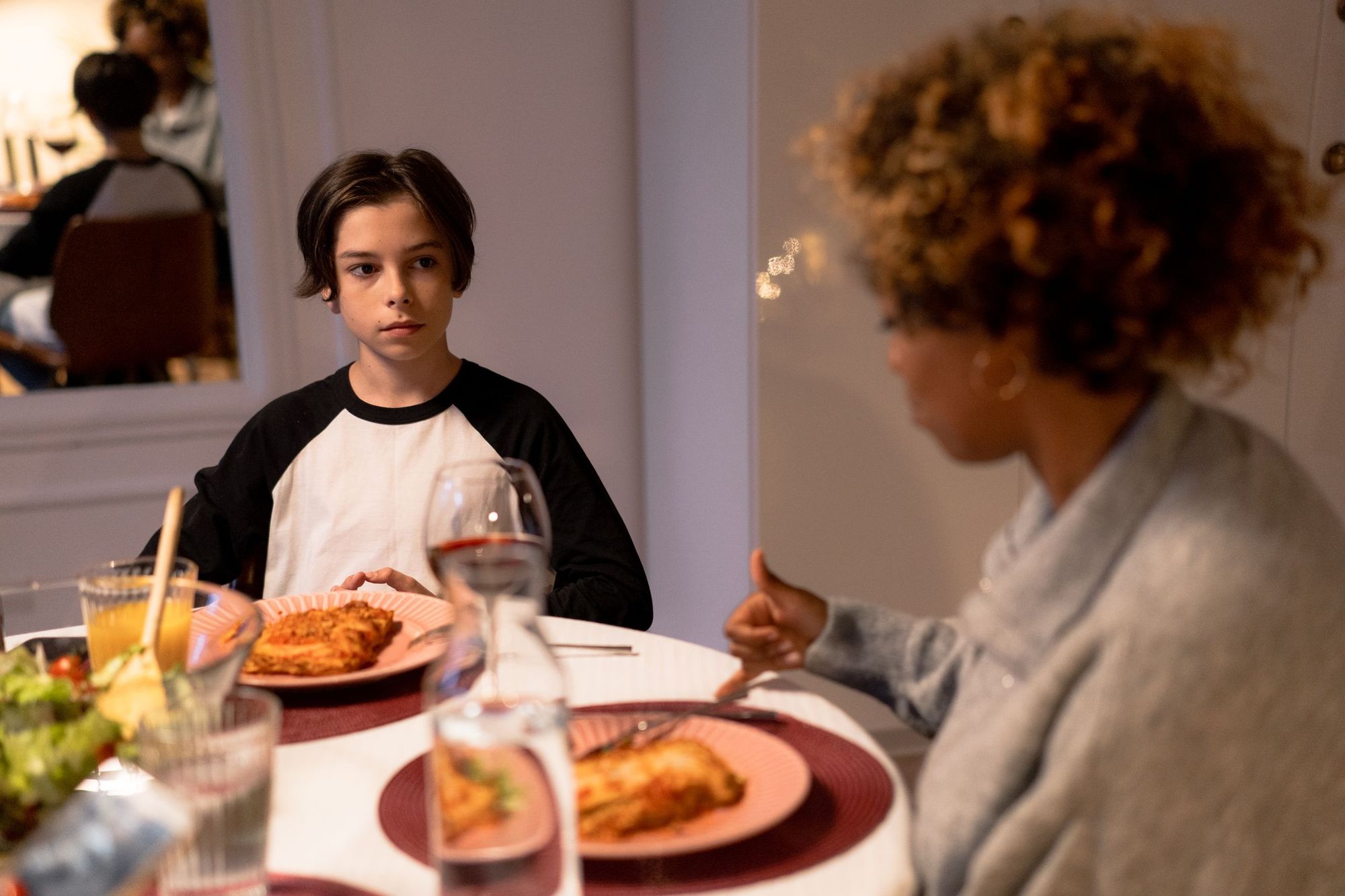 A teenage boy at the dinner table with his mother
