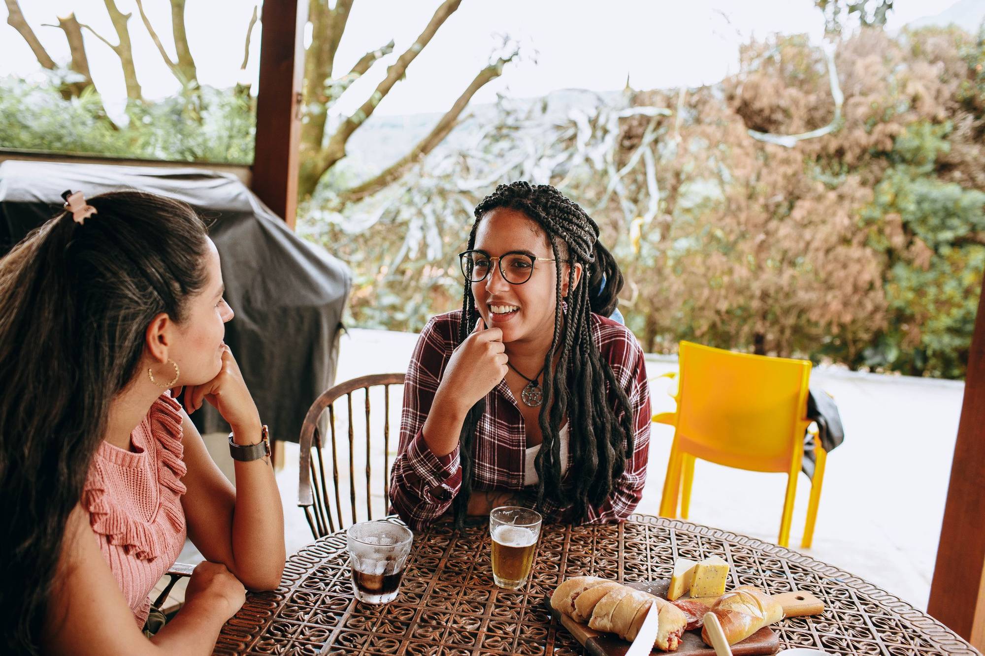 Two friends laughing together at an outdoor table