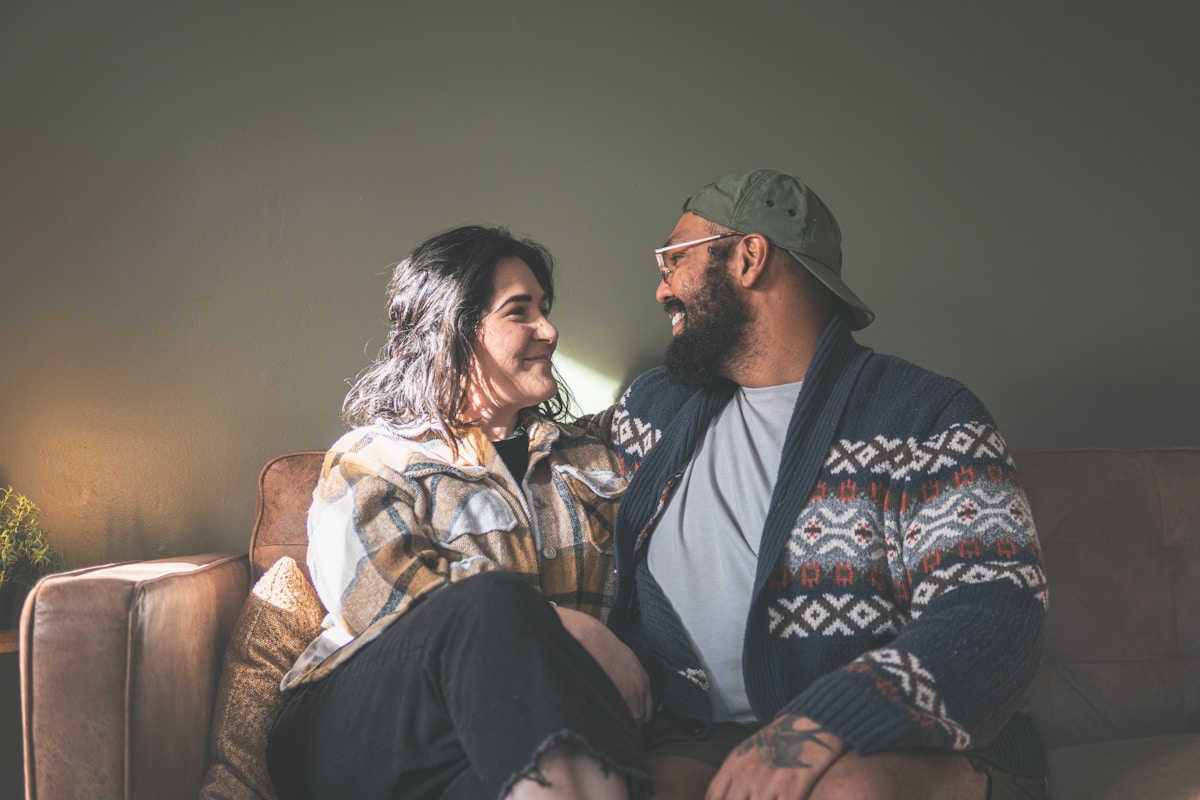A couple smiling at each other on a leather sofa