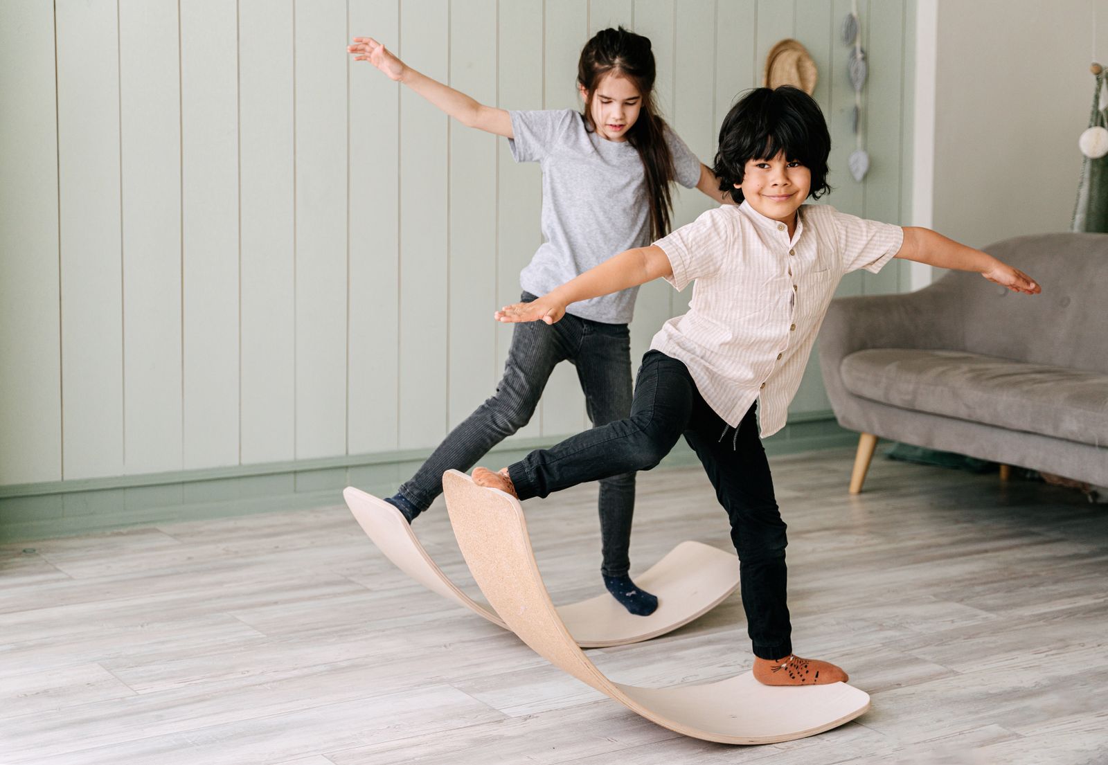 Two children balancing on wooden balance boards with their arms stretched out