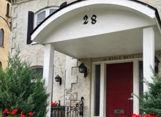 The front door of the Kitchener-Waterloo office: a red door under a white arched porch marked 28, with red flowers by the steps